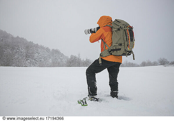 photographer working with snowshoes in covered field