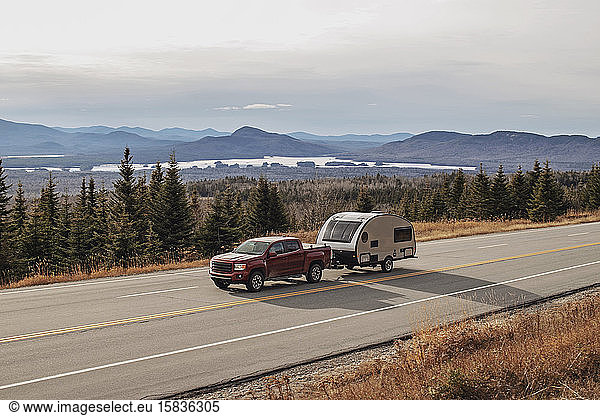 Pickup truck and RV camper drive along scenic road in Jackman  Maine