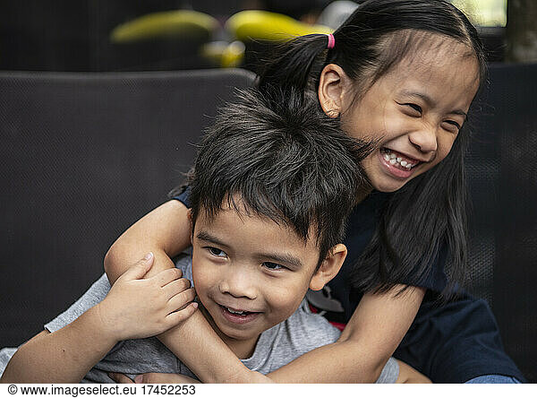 picture of two young Thai siblings playfully embrace