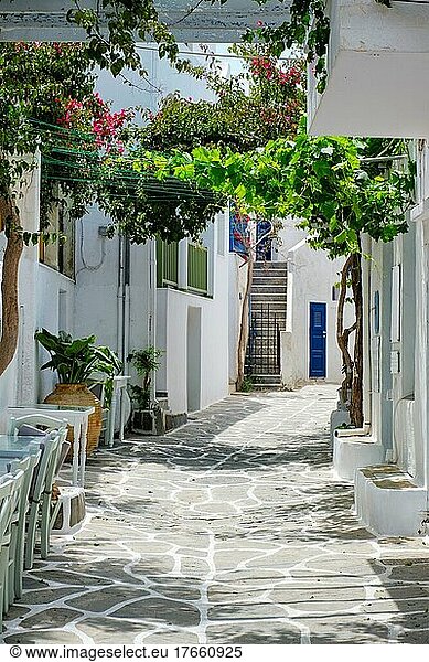 Picturesque narrow street with traditional whitewashed houses with cafe tables of Naousa town in famous tourist attraction Paros island  Greece