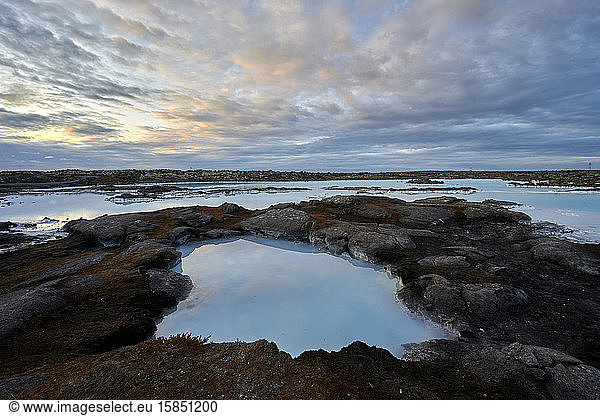 Picturesque scenery of geothermal pool with desert volcanic terrain on island