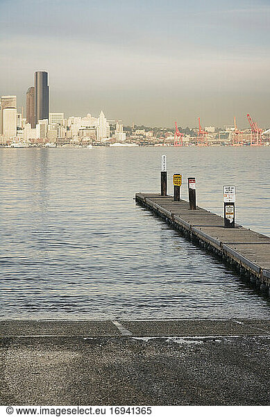Pier ins Wasser am städtischen Ufer mit Wolkenkratzern dahinter.