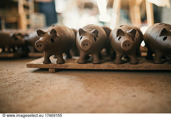 Piggy banks arranged on plank in pottery