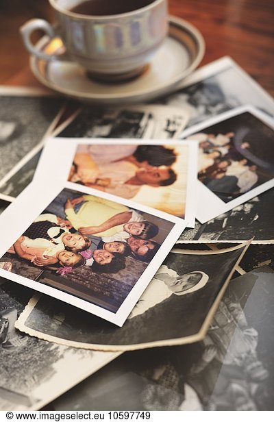 Pile of family photographs on table  next to tea cup