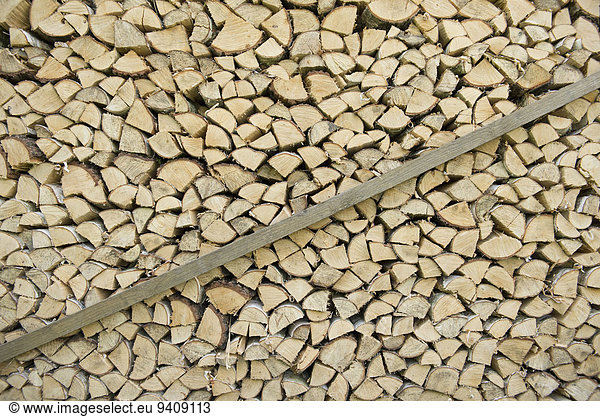 Pile of firewood stacked against wall in garden