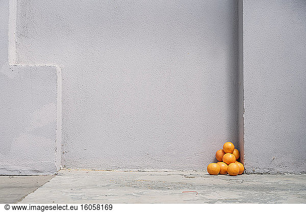 Pile of oranges in corner of a gray wall