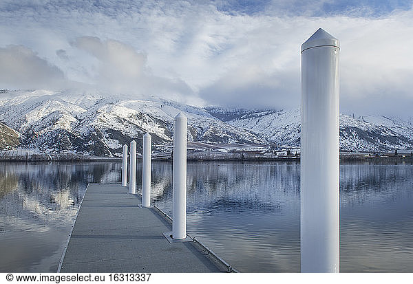 Pillars on dock at lake near snow covered mountain range