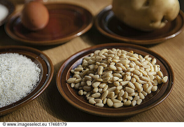 Pine nuts in plate with panellets ingredients on table