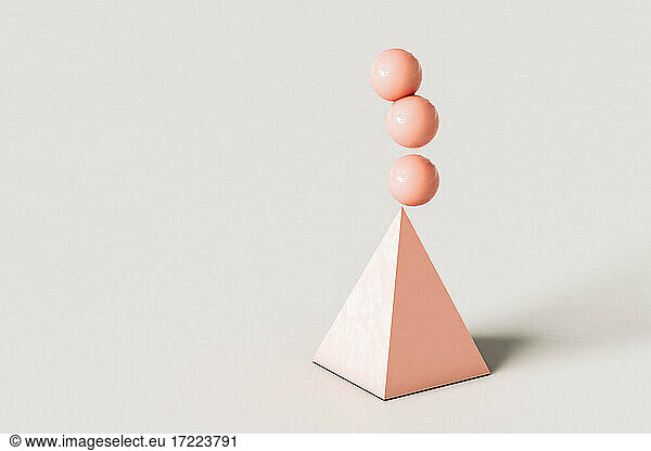 Pink abstract pyramid with three spheres balancing on top over cream colored background