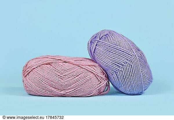 Pink and purple balls of wool on blue background