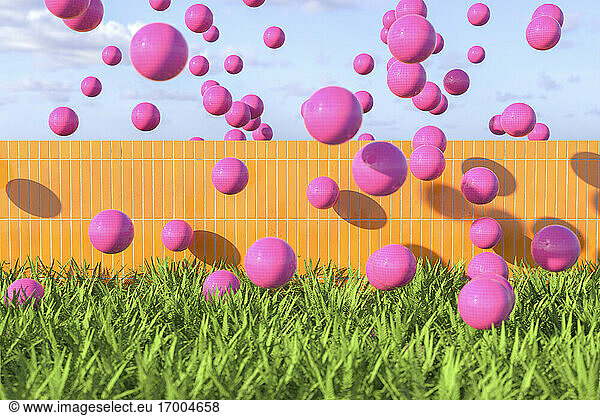 Pink balls flying over wall on a summer day