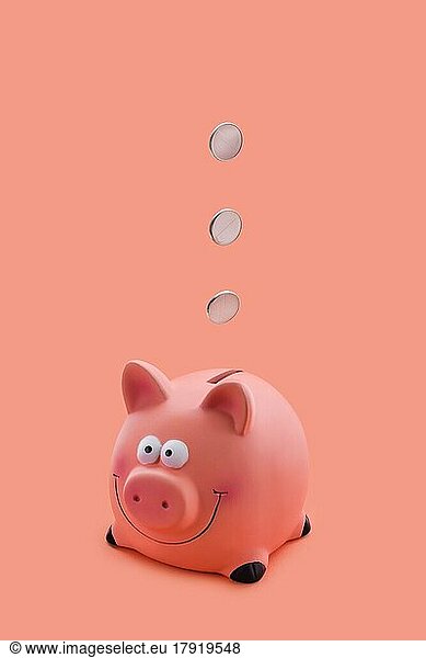 Pink piggy bank with coins falling down