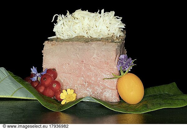 Pink roast beef with freshly grated horseradish  yellow cherry tomato  currants and flowers  food photography with black background