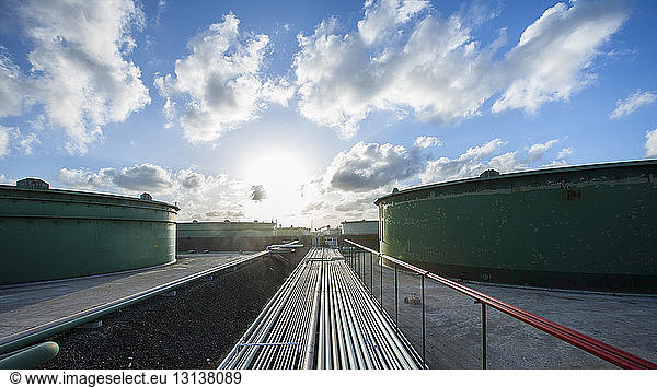 Pipelines und Lagertanks in der Industrie gegen bewölkten Himmel bei Sonnenuntergang