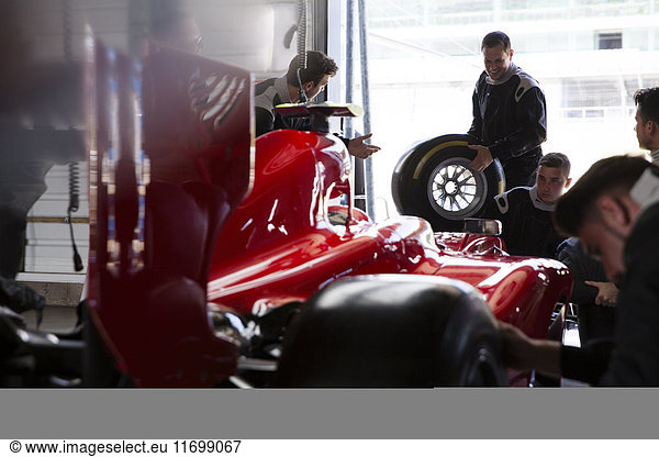 Pit crew working on formula one race car in repair garage