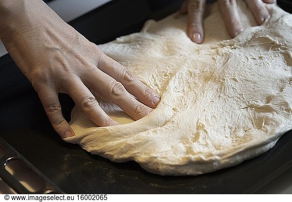 Pizzateig in das Backblech drücken.