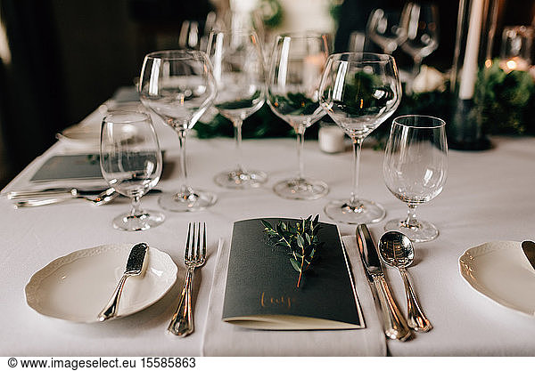 Place setting at wedding reception table with cutlery  menu and drinking glasses