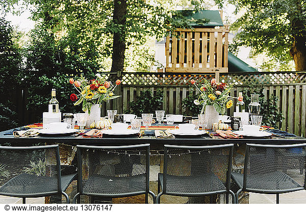 Place setting with empty chairs in backyard