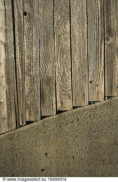 Planks of a wooden fence and concrete wall.