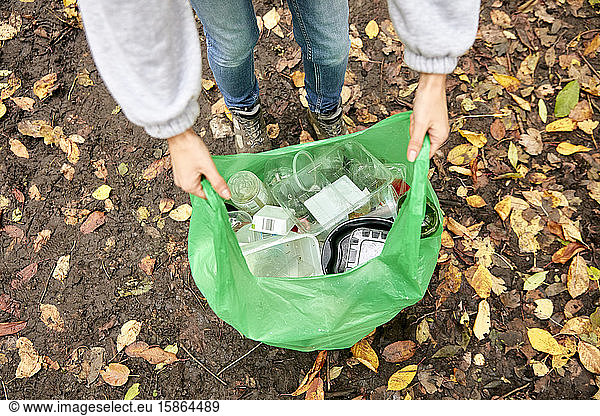 Plastic bag being held open filled with plastic litter
