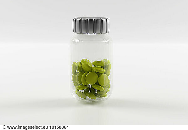 Plastic bottles filled with green pills on white background.