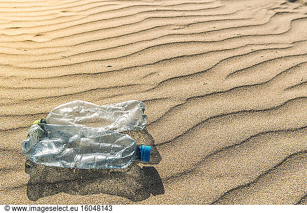 Plastic bottles lying on rippled beach sand