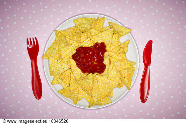 Plate of cheese nachos with salsa and red plastic cutlery on pink cloth
