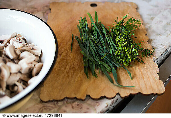 Plate of chopped mushrooms  green onions  dill on cutting board