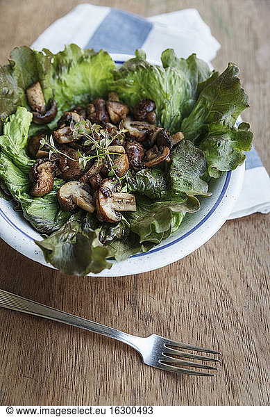 Plate of fried button mushrooms on leaf salad