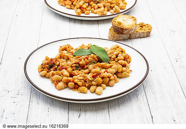 Plate of Italian baked beans (fagioli alluccelletto) with tomatoes and sage