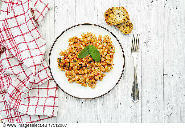 Plate of Italian baked beans (fagioli alluccelletto) with tomatoes and sage