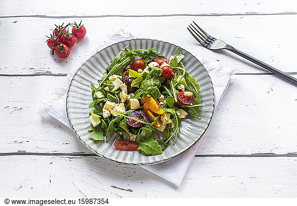 Plate of low carb vegetarian salad with arugula  tomatoes  nuts and Mozzarella cheese