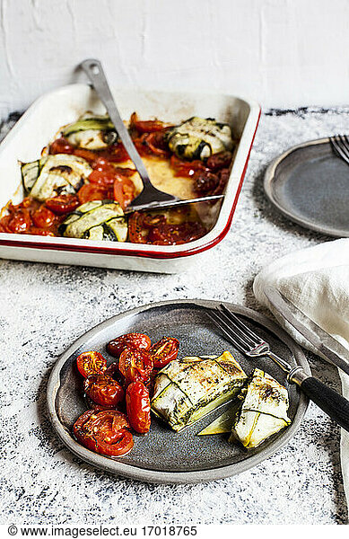 Plate of spinach and feta cheese stuffed zucchini ravioli by grilled tomato on table