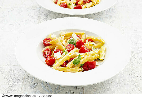 Plate of vegetarian pasta with mozzarella  cherry tomatoes and basil