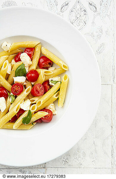 Plate of vegetarian pasta with mozzarella  cherry tomatoes and basil