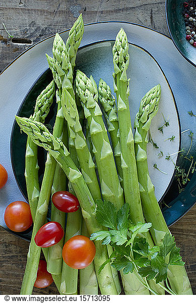 Plates and bowls with fresh cherry tomatoes  asparagus  parsley  cress and pepper