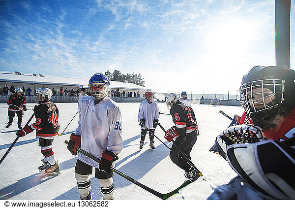 Players playing ice hockey on sunny day