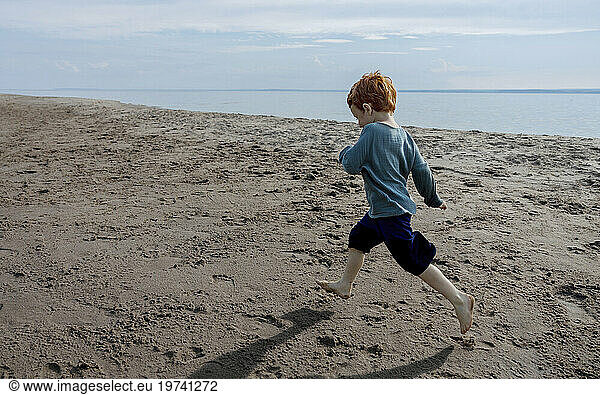 Playful boy running on sand at beach