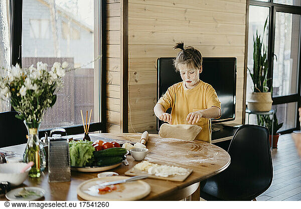 Playful boy's face covered with flour preparing dough at home