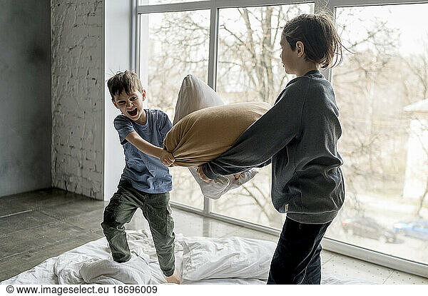 Playful brothers pillow fighting at home