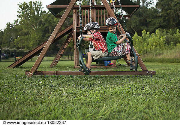 Playful brothers swinging in playground