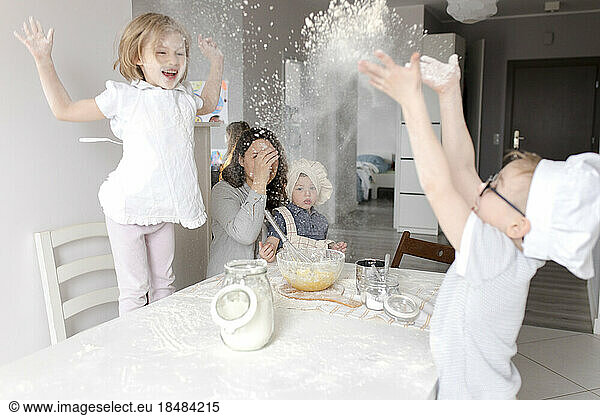 Playful children enjoying with flour in kitchen