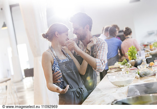 Playful couple enjoying cooking class in kitchen