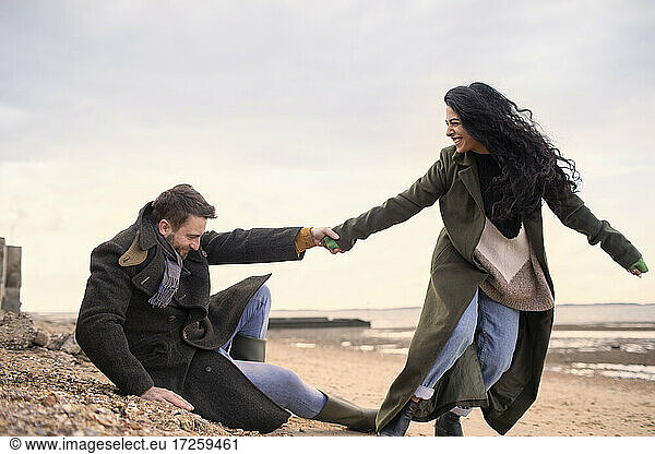 Playful couple in winter coats on beach