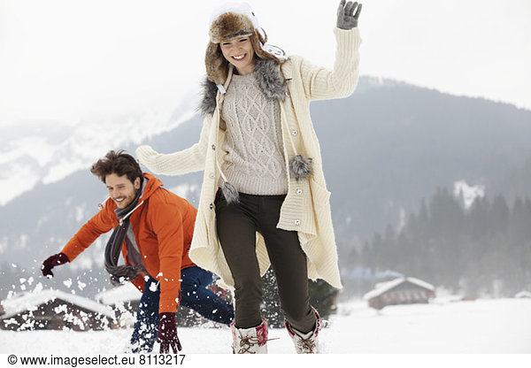 Playful couple running in snowy field