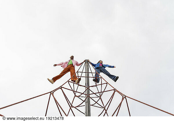 Playful couple spending leisure time on jungle gym in park