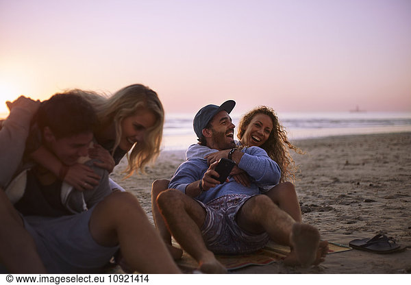 Playful couples hanging out on sunset beach