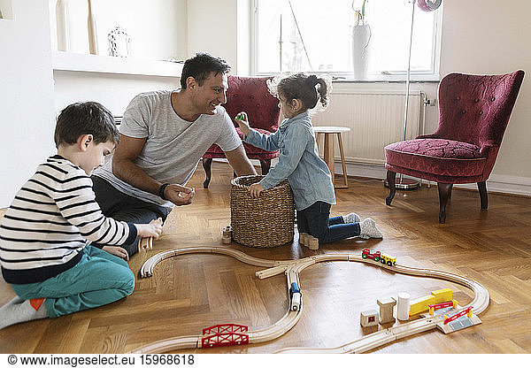 Playful daughter bonding with father while brother playing in living room