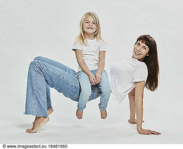 Playful daughter having fun with mother against white background