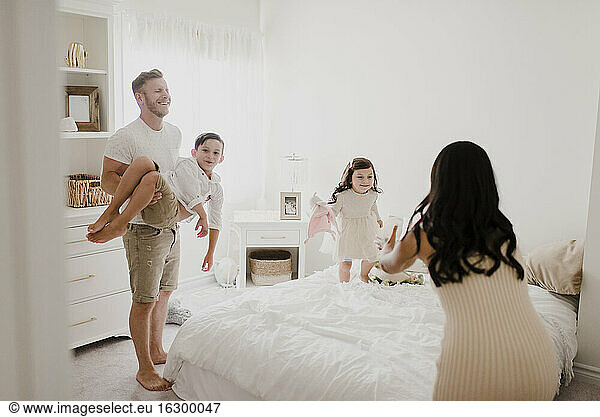 Playful family enjoying over bed in bedroom